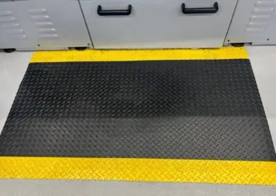 An image of black checker-plate textured safety matting in front of an industrial machine.