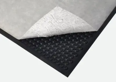 A safety mat with an absorbent layer which has been peeled back slightly to show the mat underneath.