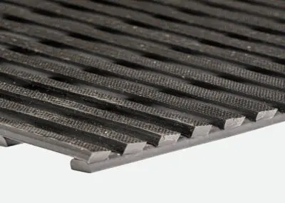 A close up of a black safety mat with regular rectangular holes.