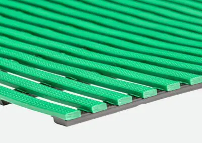 A close up of a green safety mat with regular rectangular holes.