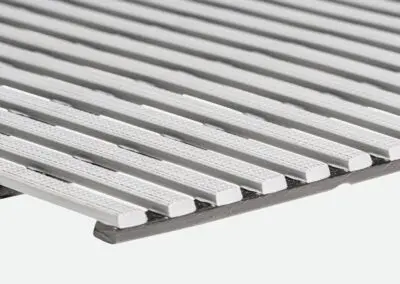 A close up of a white safety mat with regular rectangular holes.