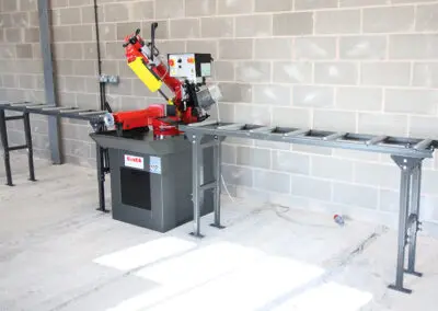350mm Roller Track, paired with a Bianco Bandsaw in a workshop environment against a wall made up of cinder blocks.