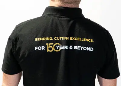 An image taken from behind of a middle-aged, bald man in a black Morgan Rushworth Polo Shirt.