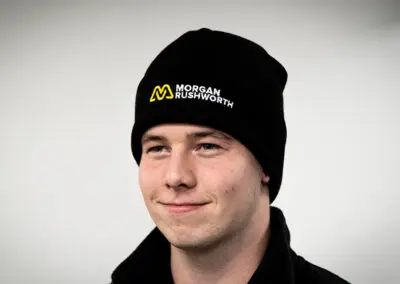 A young white boy wearing a black Morgan Rushworth beanie hat on a neutral background.