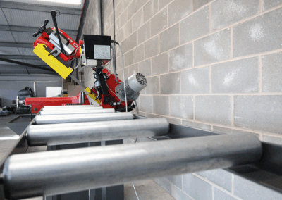 350mm Roller Track, paired with a Bianco Bandsaw in a workshop environment against a wall made up of cinder blocks.