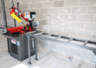 350mm Roller Track, paired with a Bianco Bandsaw in a workshop environment against a wall made up of cinder blocks.